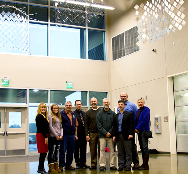 David Colbert, Tim Prentice's partner, stands with the art selection committee under the new installation, "Reflections," at Woodland High School