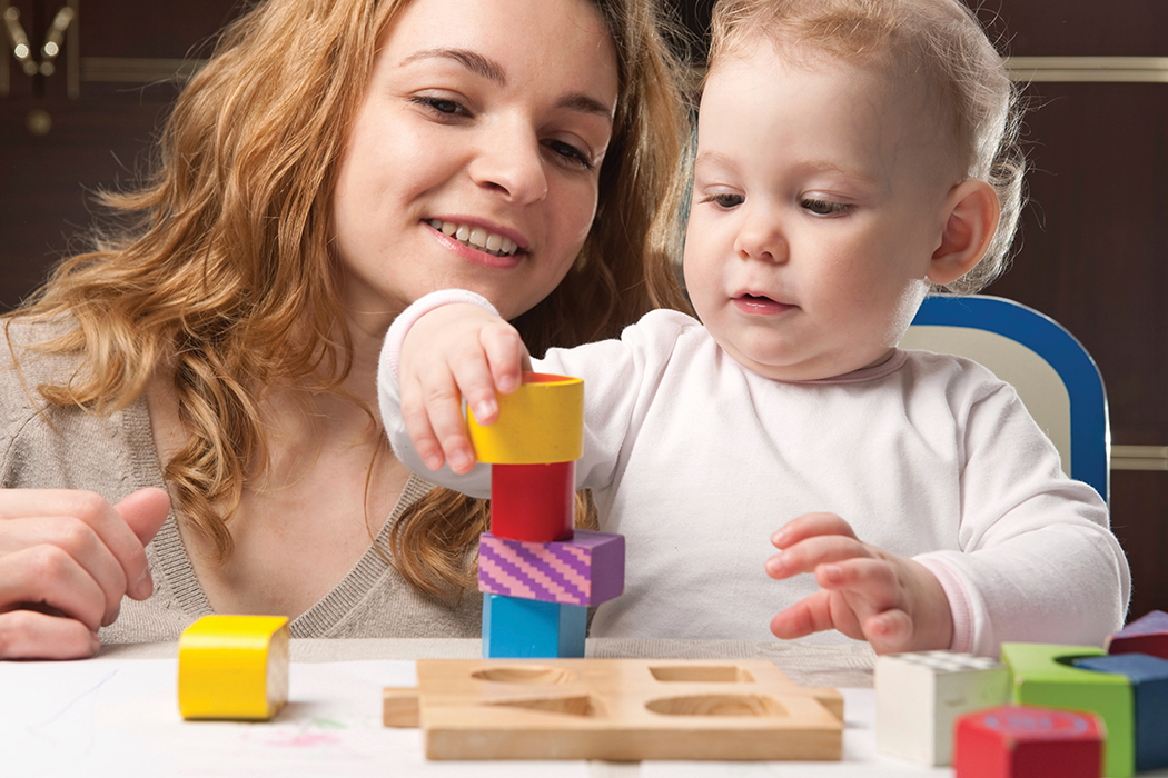 Mother and baby daughter building tower