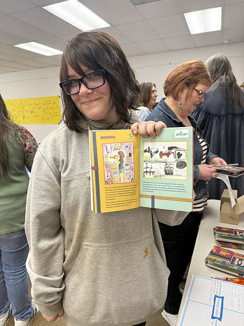 Student showing "Our Stories Our Strength" book