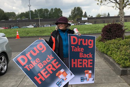 Kris Soske holds signs at the Battle Ground Police Department for the Drug Take Back event