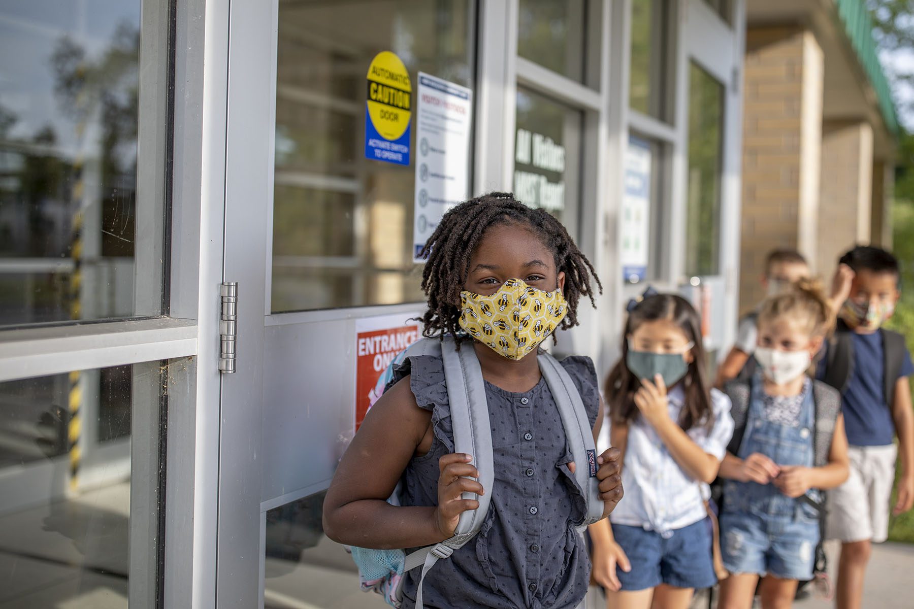Diverse group of elementary school kids go back to school wearing masks School age child care
